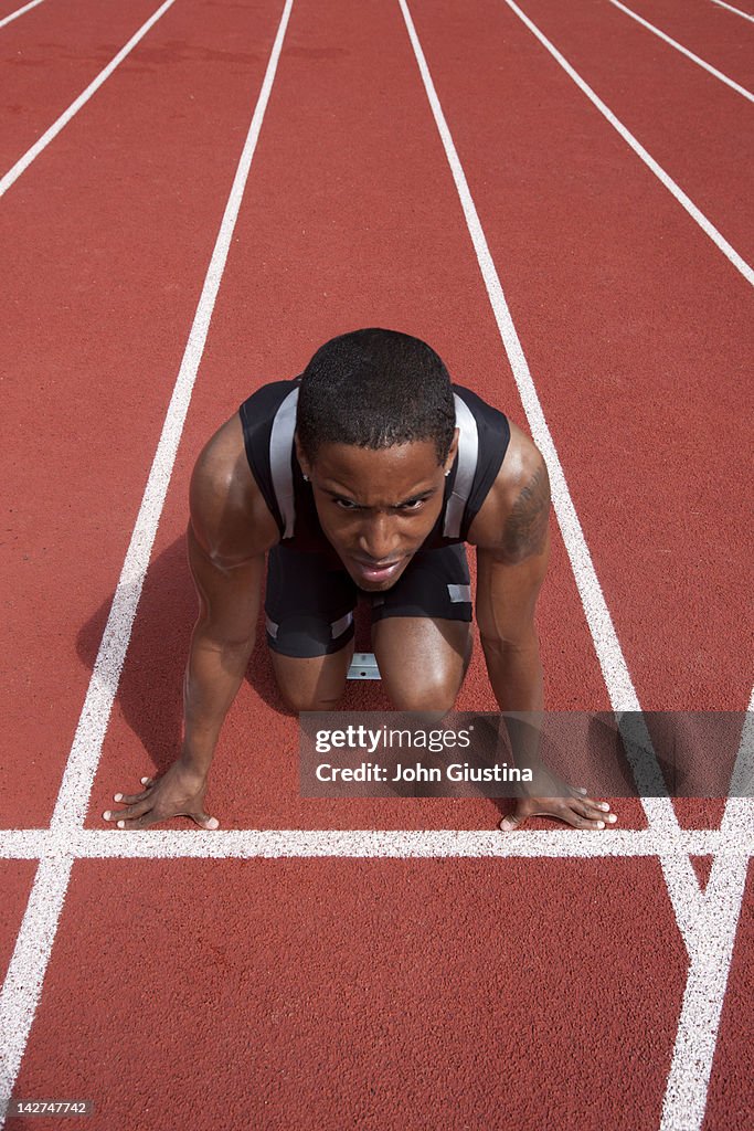 Male sprinter in blocks, awaiting starting gun