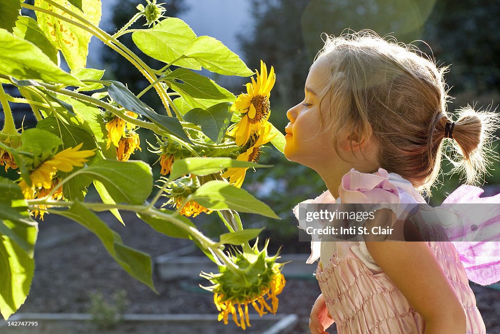 Girl (4-5) oler las flores en el jardín