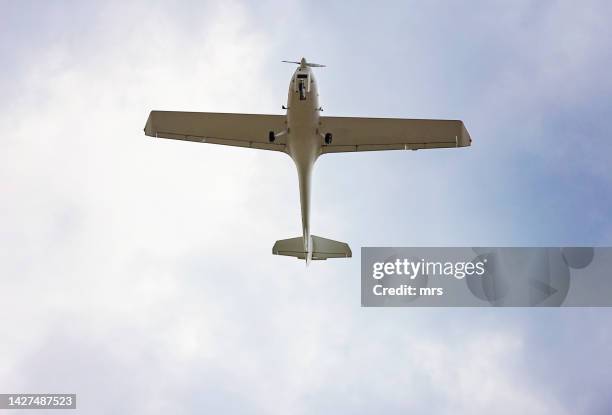 the underside of a small aeroplane in flight - propeller airplane stock pictures, royalty-free photos & images