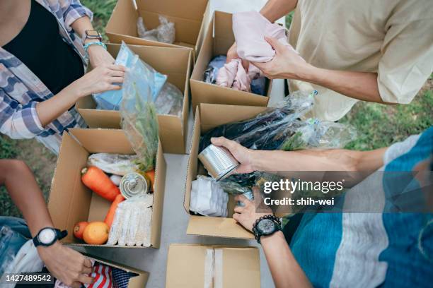 team of volunteers in the donation center sharing and packing food,clothes,water in boxes for the people in need - food distribution stock pictures, royalty-free photos & images