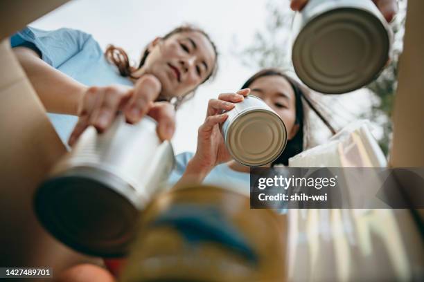 equipo de voluntarios en el centro de donación compartiendo y empacando alimentos, ropa, agua en cajas para las personas necesitadas - food distribution fotografías e imágenes de stock