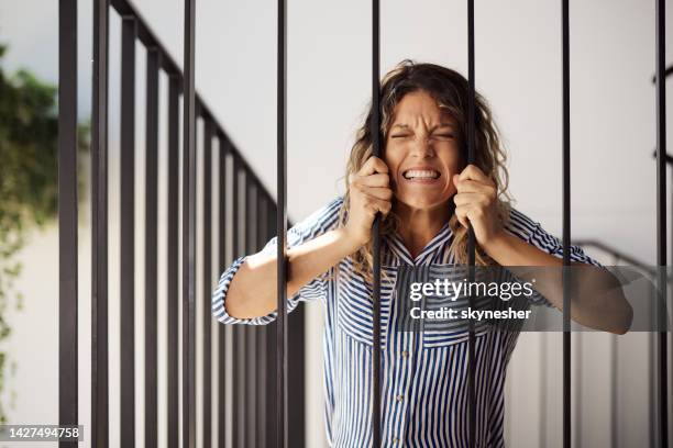 frustrated woman stuck between the bars. - escaping jail stock pictures, royalty-free photos & images