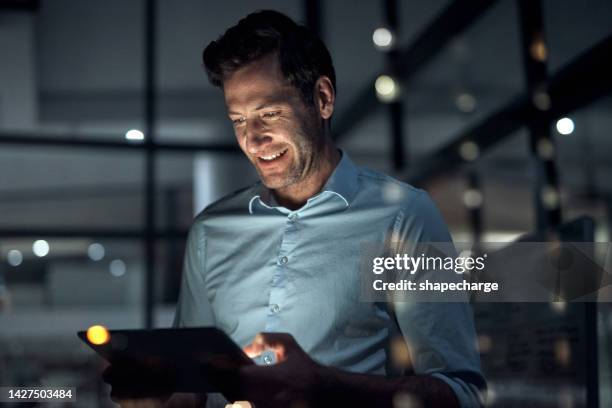 nacht im büro, ein mann mit tablet und überstunden, um einen deal abzuschließen. glücklich, lächelnd und ein geschäftsmann, der spät in einem dunklen raum arbeitet. entwickler, programmierer oder it-mitarbeiter, die sich online mit einem lächeln ve - business smile stock-fotos und bilder