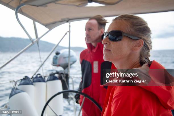 two yacht crew members on a sailboat, wearing colourful windbreakers - weather alert stock pictures, royalty-free photos & images