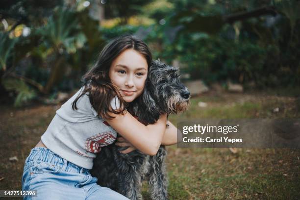 front portrait of girl looking at the camera embracing her dog outdoors - pet adoption stock-fotos und bilder