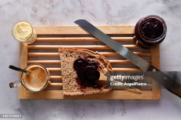 still life with the elements of a breakfast: slice of bread, butter and blackberry jam. - bread knife stockfoto's en -beelden