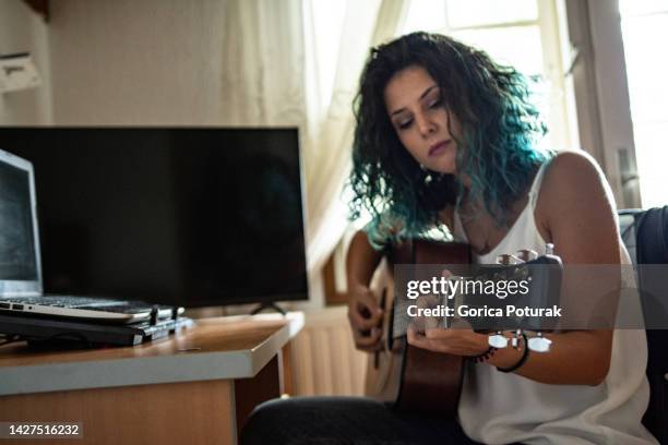 young woman playing a guitar at home - one woman only and guitar stock pictures, royalty-free photos & images