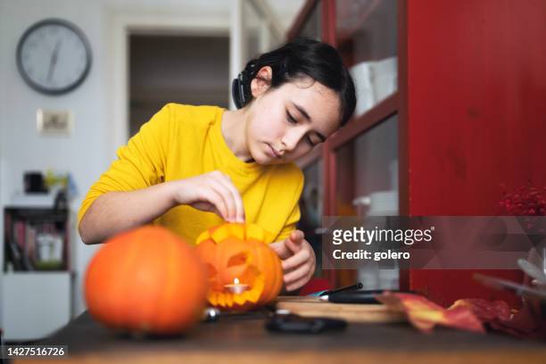 girl makes halloween pumpkin at table - halloween stencil stock pictures, royalty-free photos & images