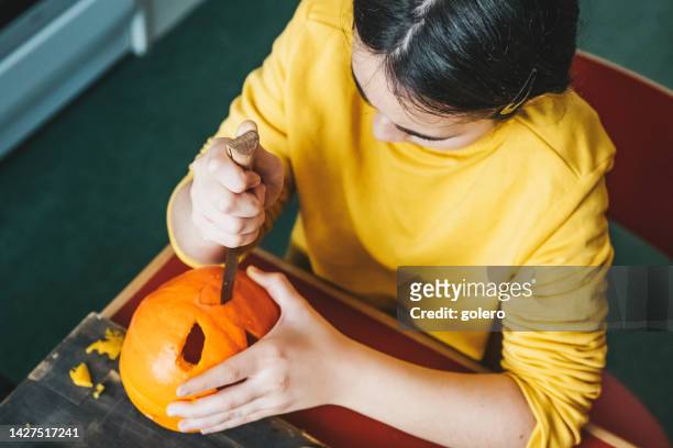 girl carving face in halloween pumpkin - halloween stencil stock pictures, royalty-free photos & images