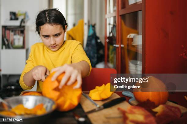 girl carving face in halloween pumpkin - halloween stencil stock pictures, royalty-free photos & images