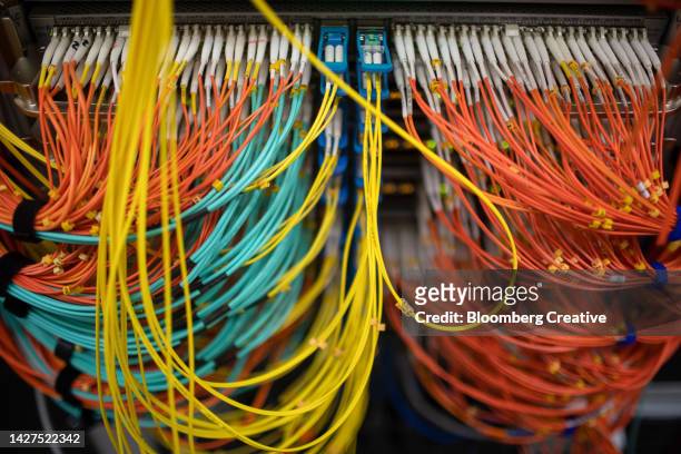 colorful cables connected to a server - glasfaser stock-fotos und bilder