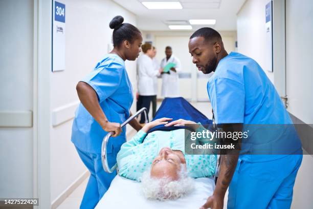 nurses pushing patient lying on stretcher - hospital trolley stock pictures, royalty-free photos & images