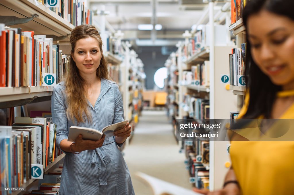 Young woman reading a book in the library