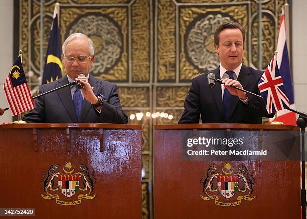 Prime Minister David Cameron and Prime Minister Najib Razak adjust their microphones at the start of a press conference at the Prime Minister's...