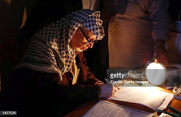 Palestinian leader Yasser Arafat works under a battery powered light inside his besieged compound September 23, 2002 in the West Bank city of...