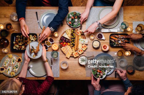 amici irriconoscibili e familiari che condividono il cibo nella sala da pranzo - utensile di portata foto e immagini stock