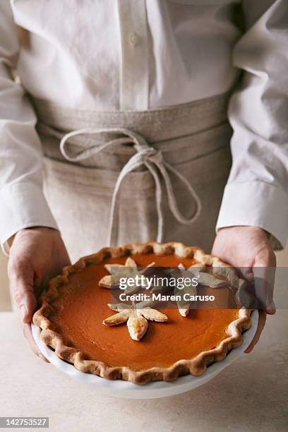 man holding a pumpkin pie with leaf details - thanksgiving indulgence stock pictures, royalty-free photos & images