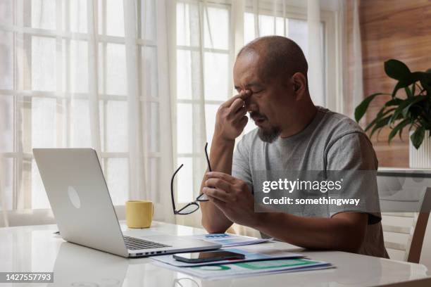 adult man is tired and rubbing his eyes while working - rubbing eyes stock pictures, royalty-free photos & images