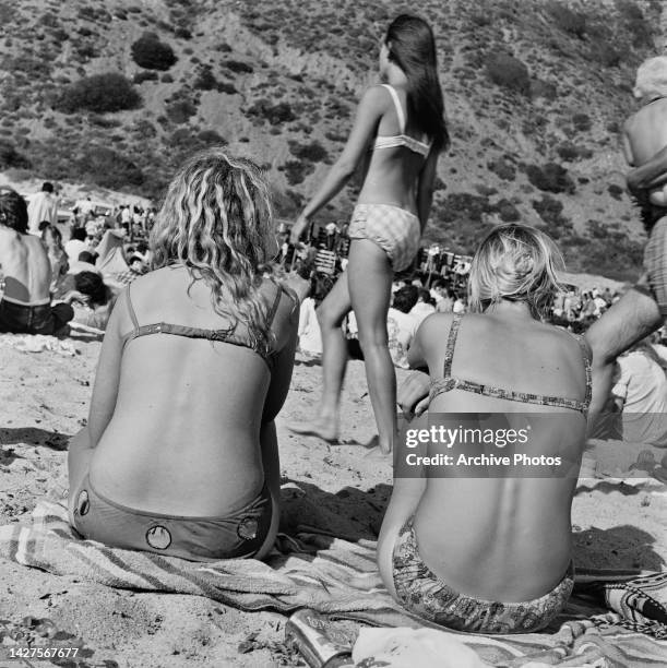 Rear view of two women wearing bikinis sitting on a towel at the love-in held on Easter Sunday in Elysian Park, one of the largest parks in Los...