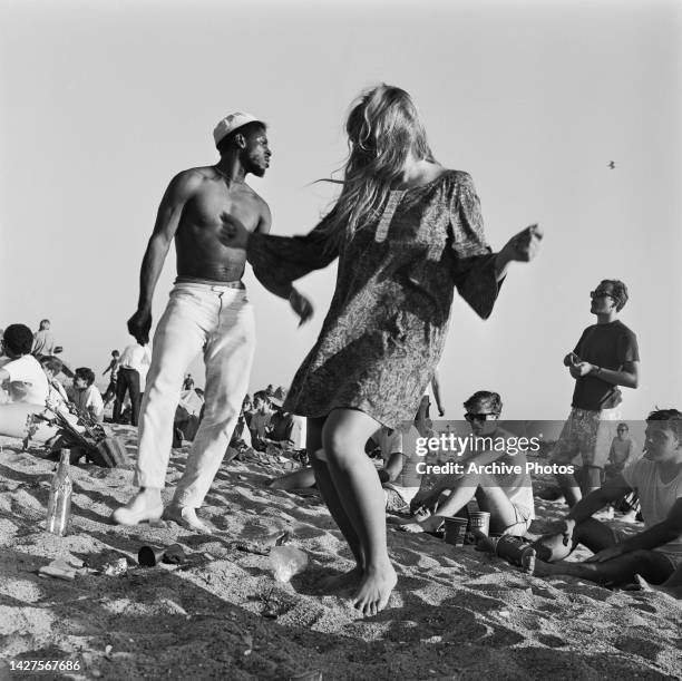 Low angle view of a woman in a paisley pattern dress dancing beside an shirtless man, as others sit around, at the love-in held on Easter Sunday in...