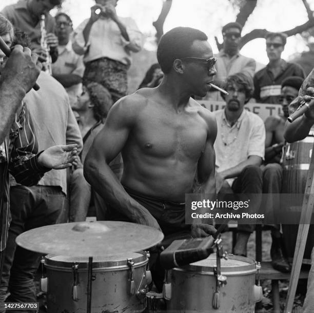 An shirtless drummer, wearing sunglasses and smoking a cigarette as he performs at the love-in held on Easter Sunday in Elysian Park, one of the...
