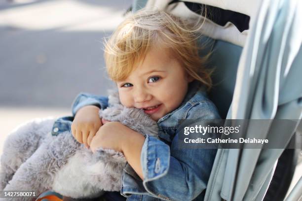 a 2 year old little girl smiling in her stroller - prams stock pictures, royalty-free photos & images