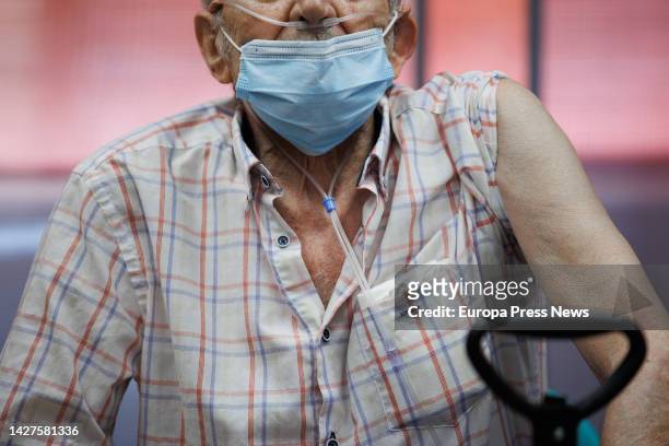 An elderly man prepares his arm for the injection of the Moderna dose during the start of the administration of the fourth dose of the COVID-19...