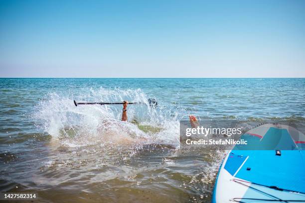 man falling off stand up paddle board - paddle board men imagens e fotografias de stock