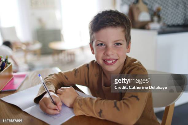9 year old boy doing his homework in the kitchen - 10 year fotografías e imágenes de stock