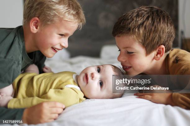 3 brothers posing together laying on a bed - little brother stock pictures, royalty-free photos & images