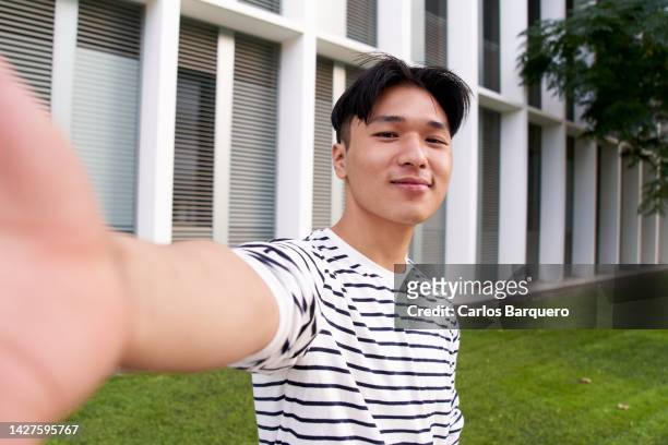 cheerful asian man taking selfie of him with cellphone, outside campus university. social media usage. - selfie imagens e fotografias de stock