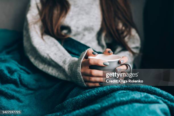 cold loneliness in wet season. cropped woman in warm clothes drink hot tea, wrapped in blanket - cold woman stockfoto's en -beelden