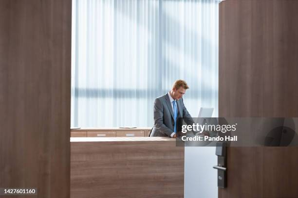 friendly businessman working in his office at the counter, view through open doors - banken versicherungen user stock-fotos und bilder