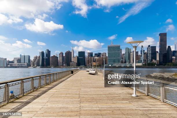 pier in queens with view of midtown manhattan skyline, new york city, usa - queens stockfoto's en -beelden