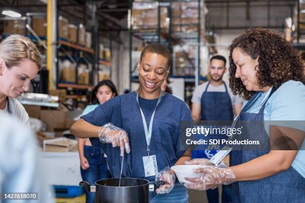 multiracial group volunteers at food bank soup kitchen - food pantry stock pictures, royalty-free photos & images