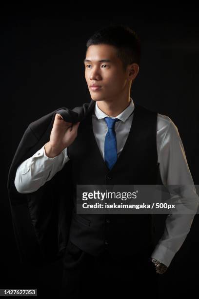 businessman standing against black background - waistcoat stock-fotos und bilder