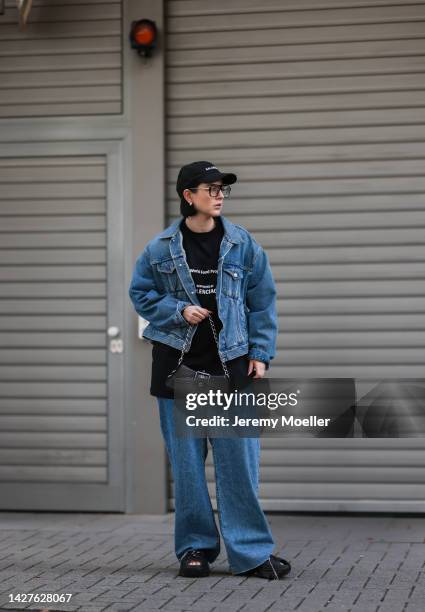 Maria Barteczko seen wearing a blue asymmetric denim jacket by Balenciaga, a black printed longsleeve by Balenciaga, a destroyed wide leg jeans by...