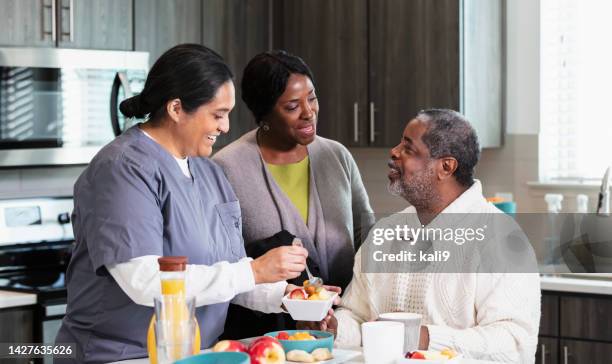 senior couple, caregiver in kitchen serving healthy snack - nutritionist stock pictures, royalty-free photos & images