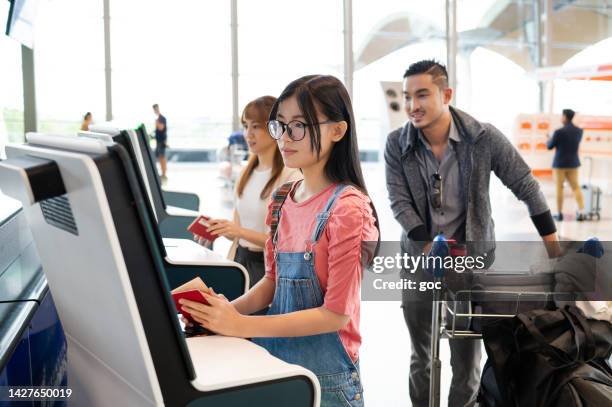 young asian girl self check in and print boarding pass with self check in kiosk at airport terminal - kuala lumpur airport stock pictures, royalty-free photos & images