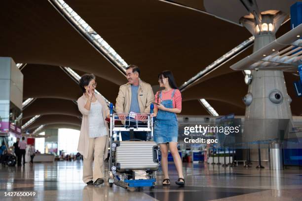 happy asian grandparents with their granddaughter travelling together for holiday vacation - kuala lumpur airport stockfoto's en -beelden