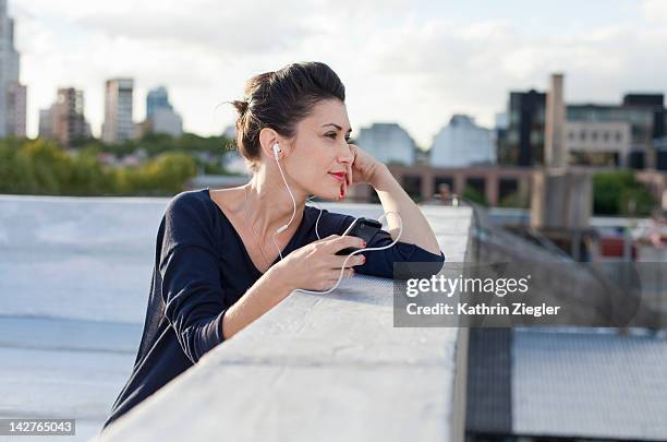 elegant woman listening to music on a rooftop - buenos aires rooftop stock pictures, royalty-free photos & images