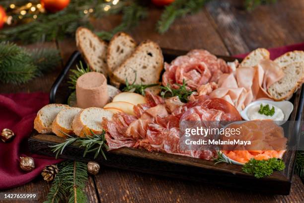 aperitivo tabla de charcutería con jamón, salami, salmón y pan para la celebración festiva de navidad en cocina rústica - antipasto fotografías e imágenes de stock