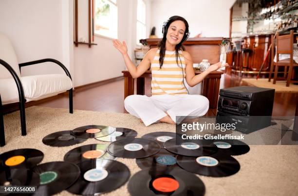 young woman enjoying listening to vinyl record from a music player at home - personal stereo stockfoto's en -beelden