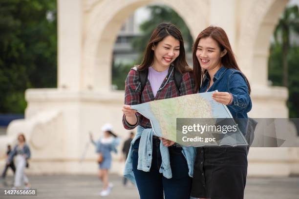 two female asian travelers holding street map while walking in the city - taipei map stock pictures, royalty-free photos & images