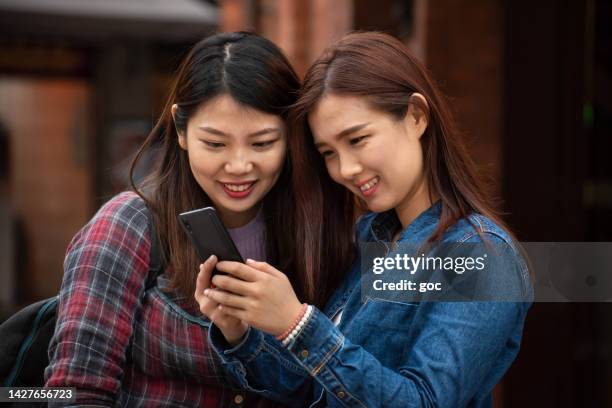 two smiling asian women video calling with smart phone at outdoor - pessoas bonitas imagens e fotografias de stock
