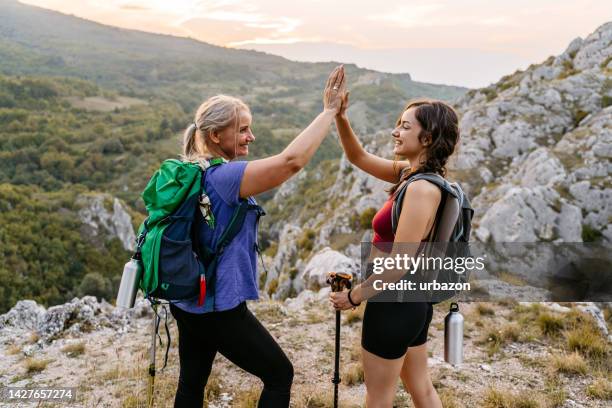 mother and daughter high-fiving after getting on top of the mountain - mom cheering stock pictures, royalty-free photos & images