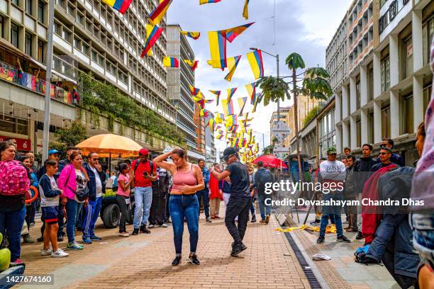 bogotá, colombia - a spectator joins a male  street dancer and people enjoy watching the couple dance. it is the weekend. - colombia dance stock pictures, royalty-free photos & images