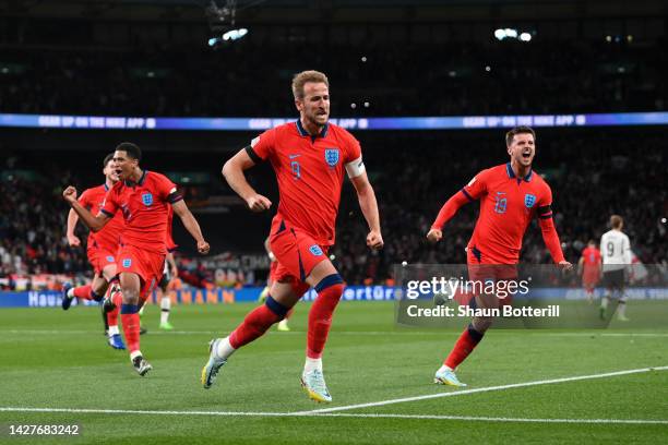 Harry Kane of England celebrates with team mates Mason Mount and Jude Bellingham after scoring their team's third goal from the penalty spot during...