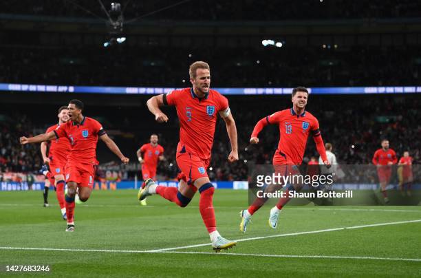 Harry Kane of England celebrates with team mates Mason Mount and Jude Bellingham after scoring their team's third goal from the penalty spot during...