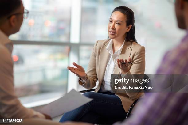 multiracial asian hispanic pacific islander mature woman talking with colleagues in business office in meeting - annual woman stockfoto's en -beelden